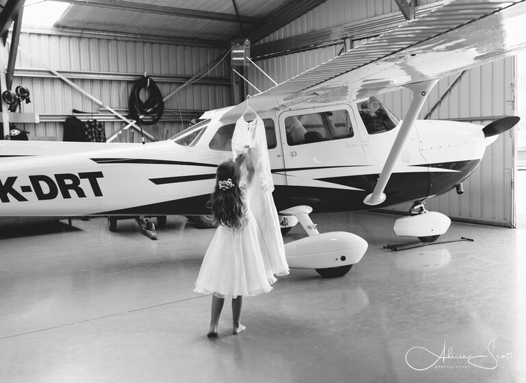 Image of flower girl with an airplane at Martinborough airstrip taken by Alicia Scott - Wairarapa wedding photographer